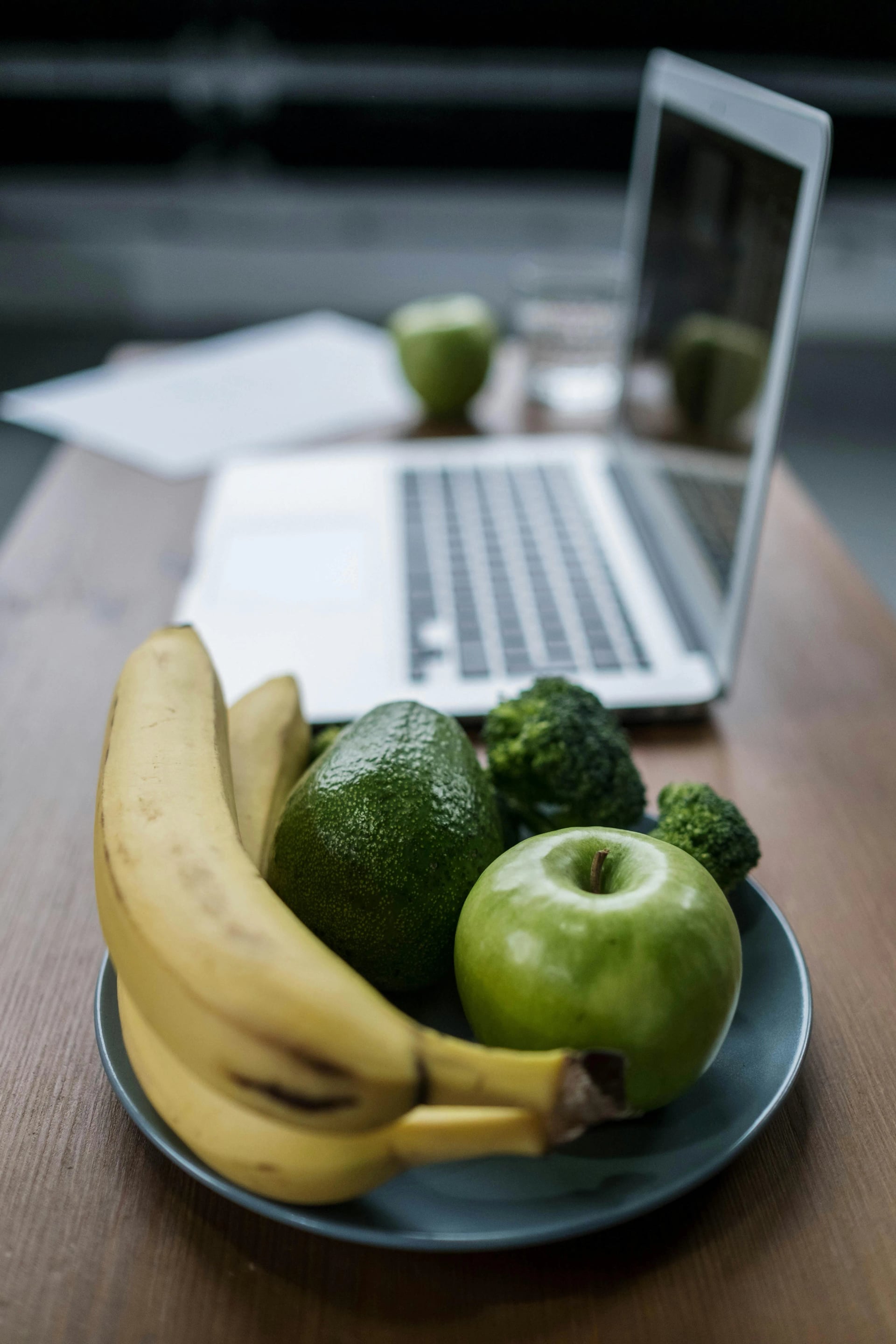 Pessoa trabalhando no computador com alimentação saudável na mesa